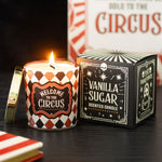 Scented candle with 'Welcome to the Circus' design and packaging on a dark surface.