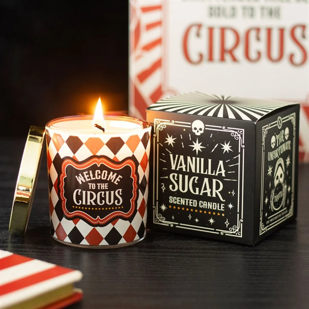 Scented candle with 'Welcome to the Circus' design and packaging on a dark surface.
