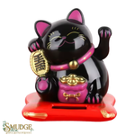 Black cat figurine with pink accents holding a gold coin, on a white background.