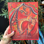 A hand holds a red-covered journal titled 'Mother Mary Oracle: Journal and Book of Sacred Practices' by Alana Fairchild. The cover features a colorful illustration of the Virgin Mary in red and orange tones with roses.