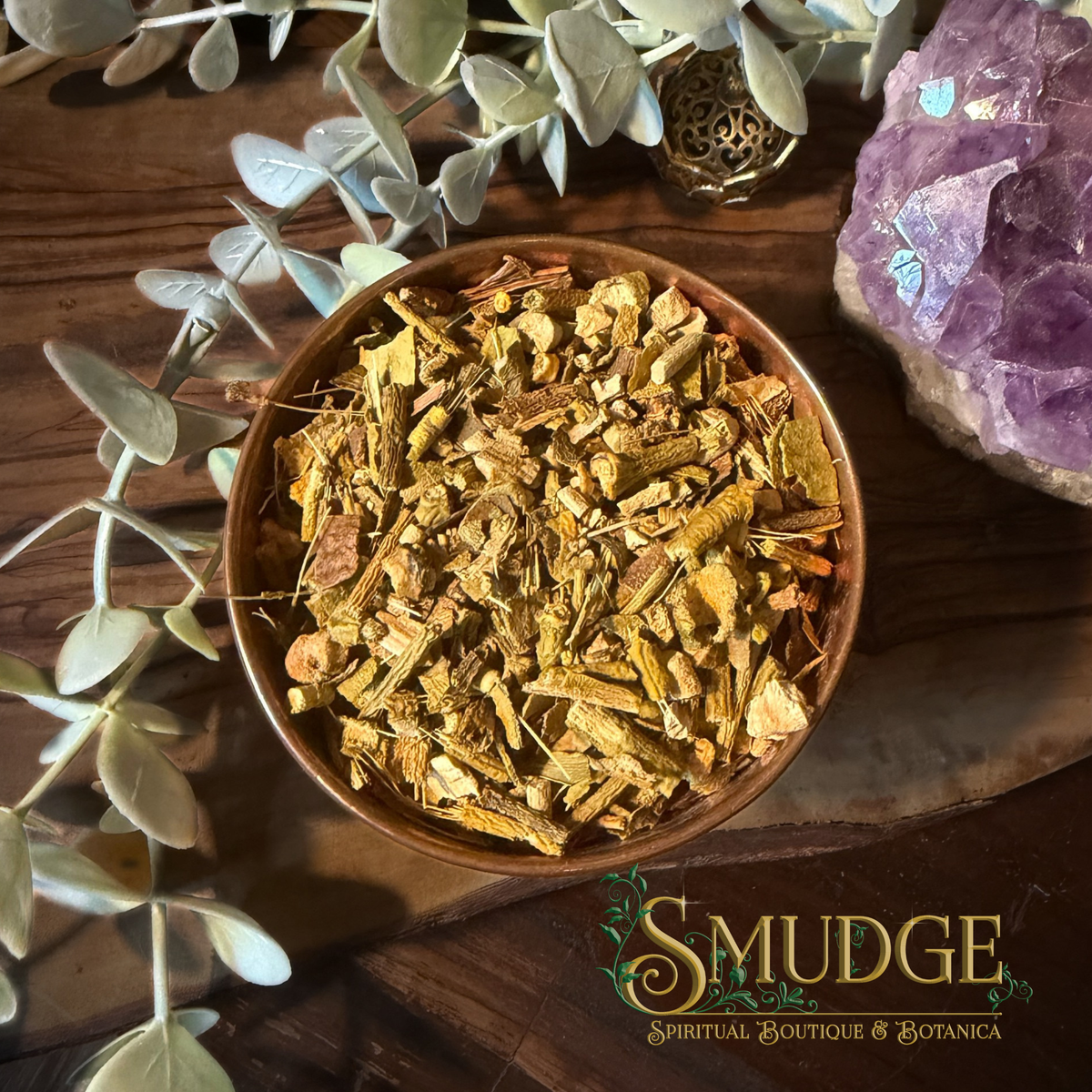 A bowl of chopped, dried mistletoe european on a wooden background with eucalyptus and an amethyst crystal beside it. 