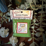 Pack of Aunty Conjure Incense Powder labeled 'Money Magnet' with decorative text on a wooden surface with greenery.