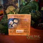 Lo scarabeo moonstone rune stone set on a table with green leaves in the background.