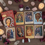 Collection of tarot cards and book titled 'Mother Mary Oracle' on a wooden surface with flowers.