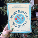 A hand holds a book titled 'The Only Tarot Book You'll Ever Need' by Skye Alexander and Mary Shannon. The book has a cream cover with a light blue border and colorful tarot card illustrations.