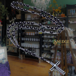 Black beaded rosary with a cross on a blurred store shelf background