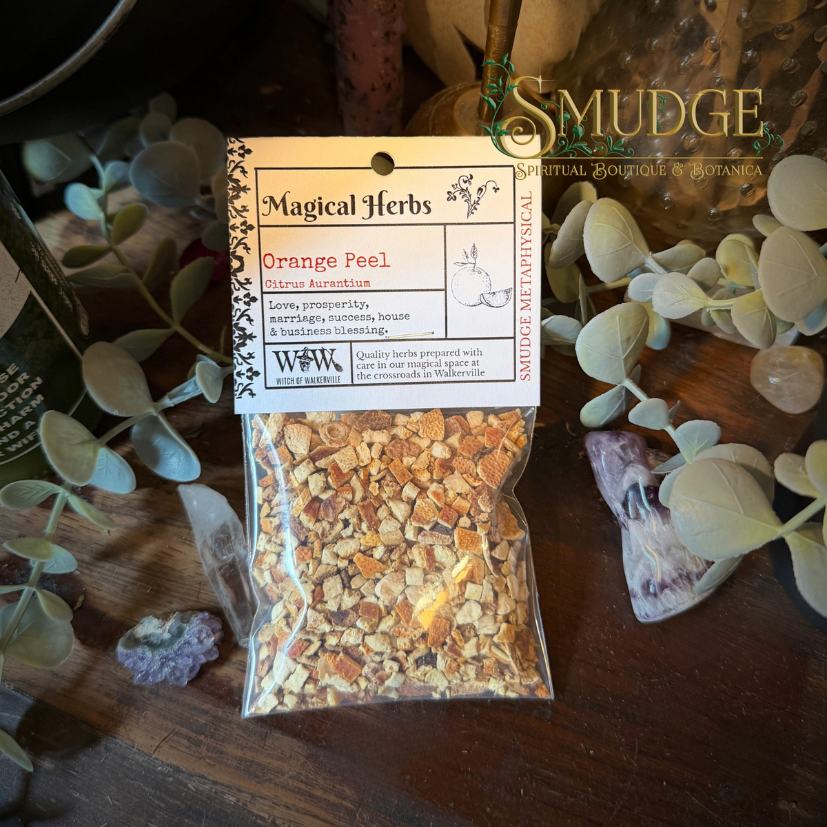 A package of orange peel from smudge Metaphysical on a wooden table with botanical leaves around it.