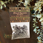 Palo Santo resin package with decorative label on a wooden surface with greenery.