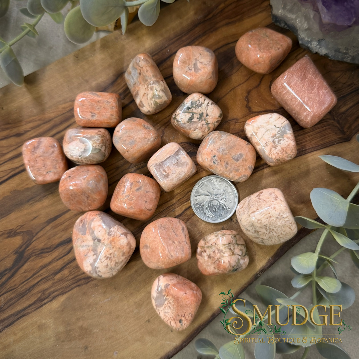 Peach moonstone tumbled stone on a wooden background.