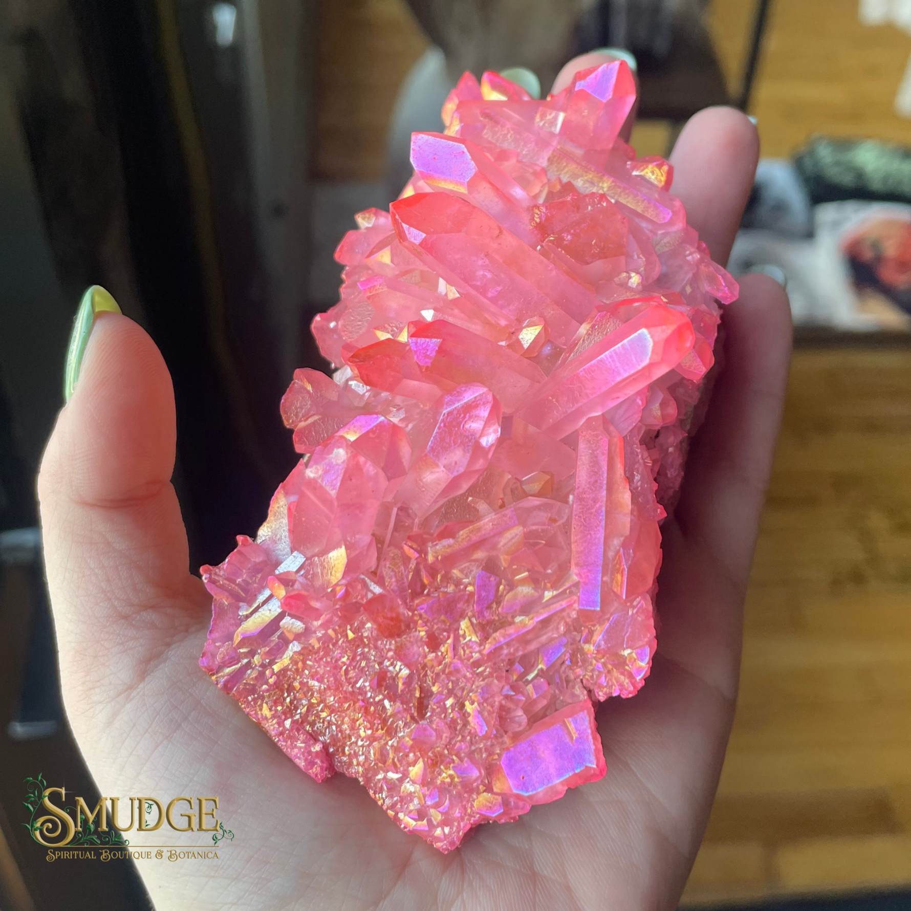 Pink crystal rock held in a hand with a blurred background