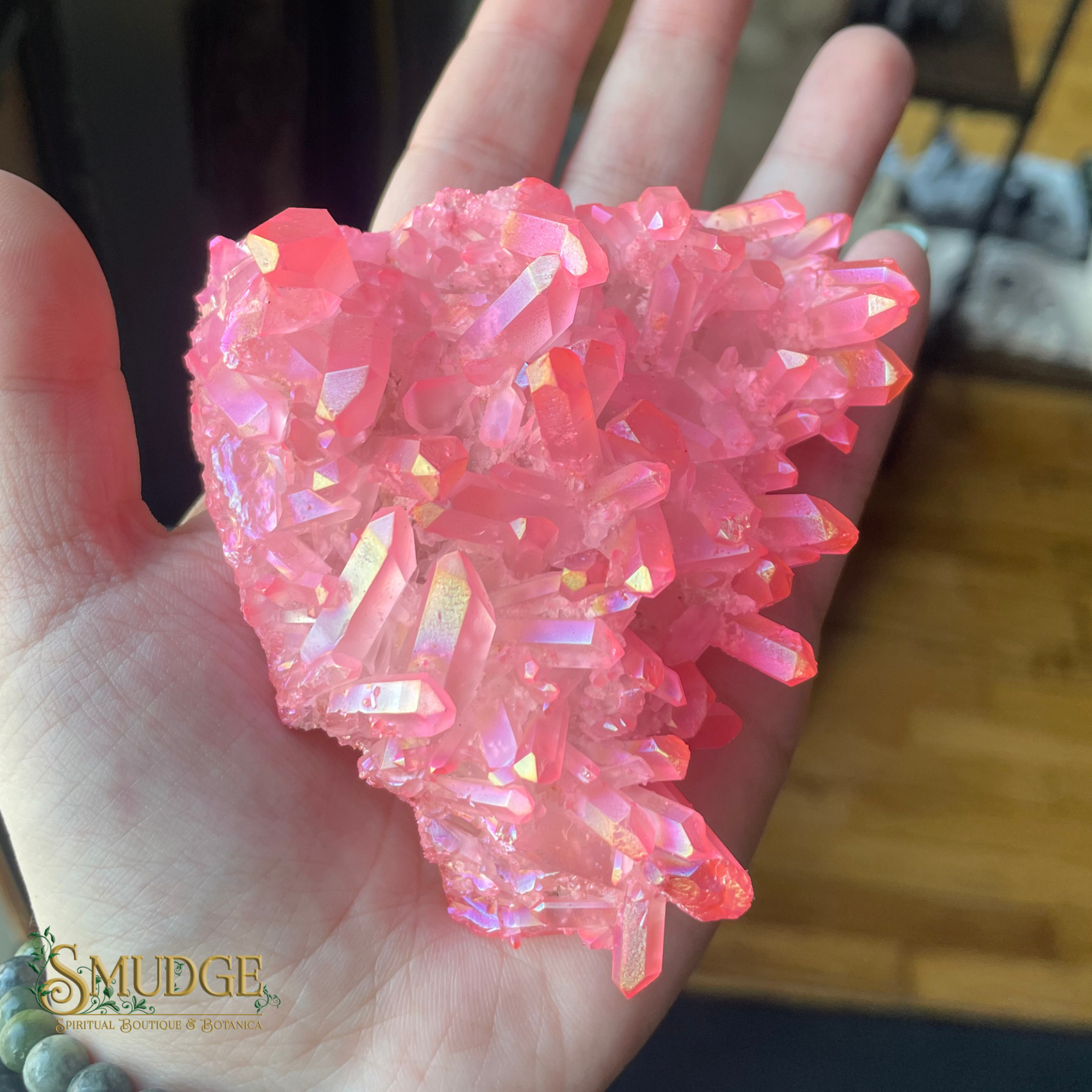 Pink crystal cluster held in a hand with 'Smudge' brand logo.