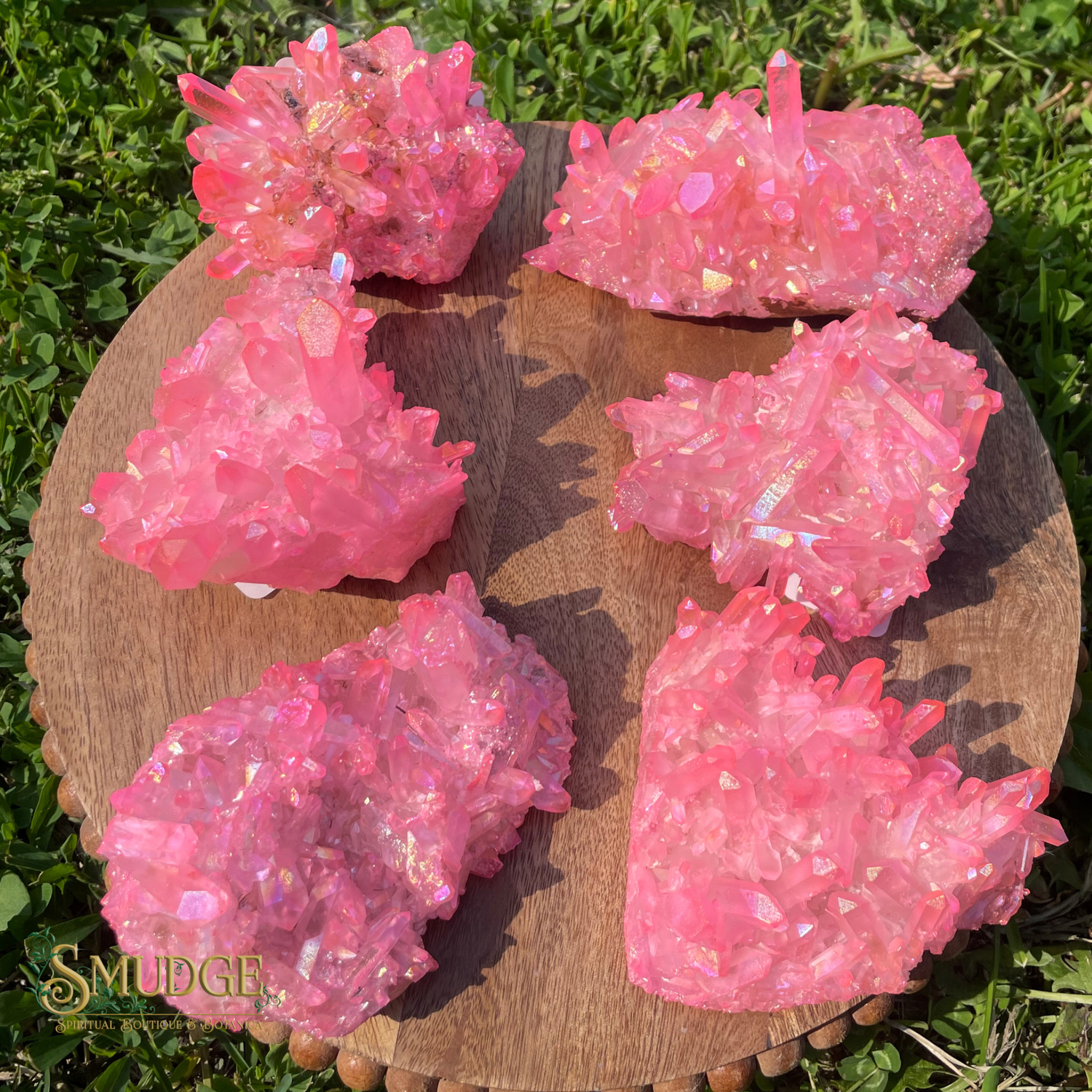 Pink crystal-like objects on a wooden board with grass in the background