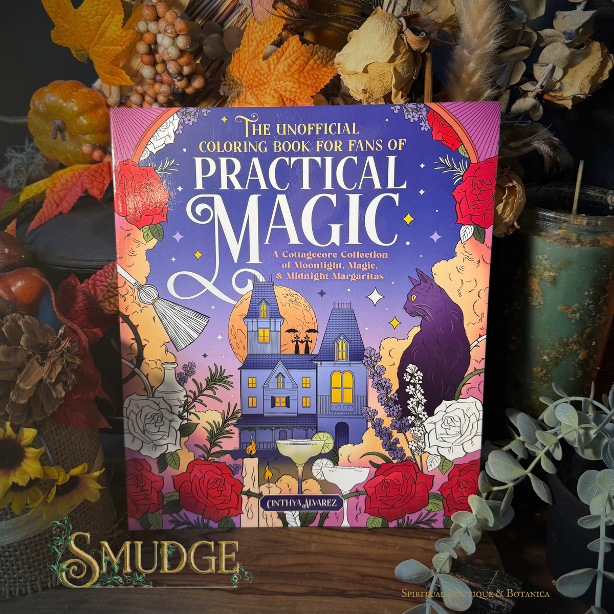 The Unofficial Coloring Book for Fans of Practical Magic by Intiza Aguarez, displayed in a styled flat-lay setting with autumn leaves, dried flowers, and a green glass jar.