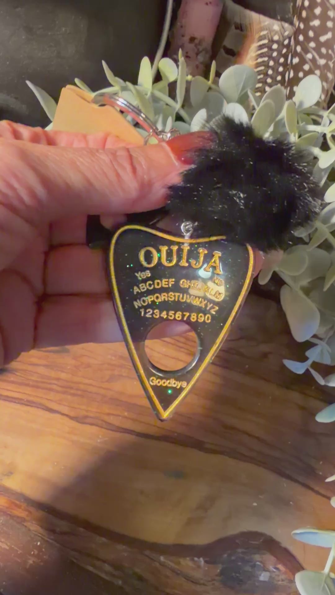 green glittery ouija planchette style keychain being shown in a video. 