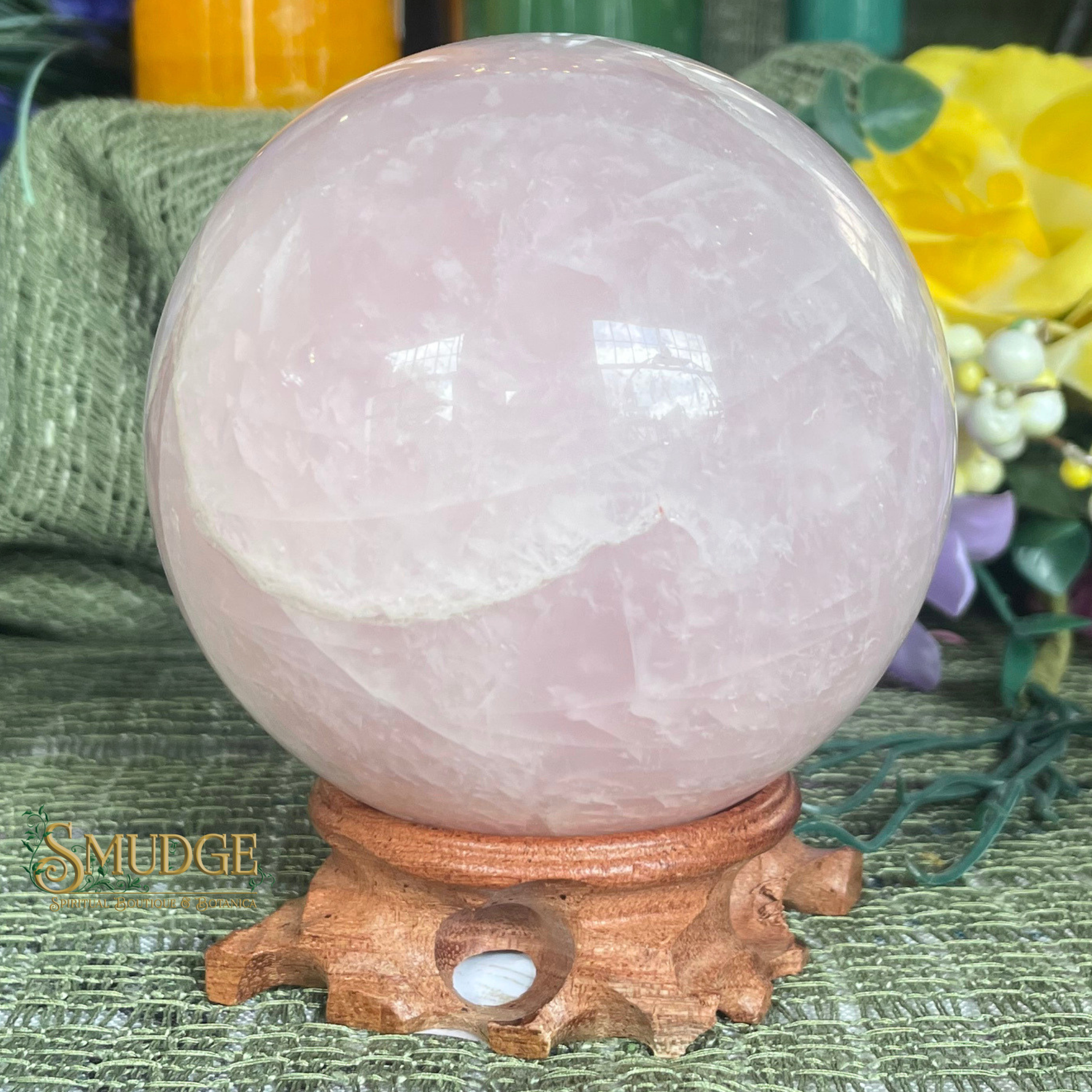 Rose quartz crystal sphere on a wooden stand with a blurred background