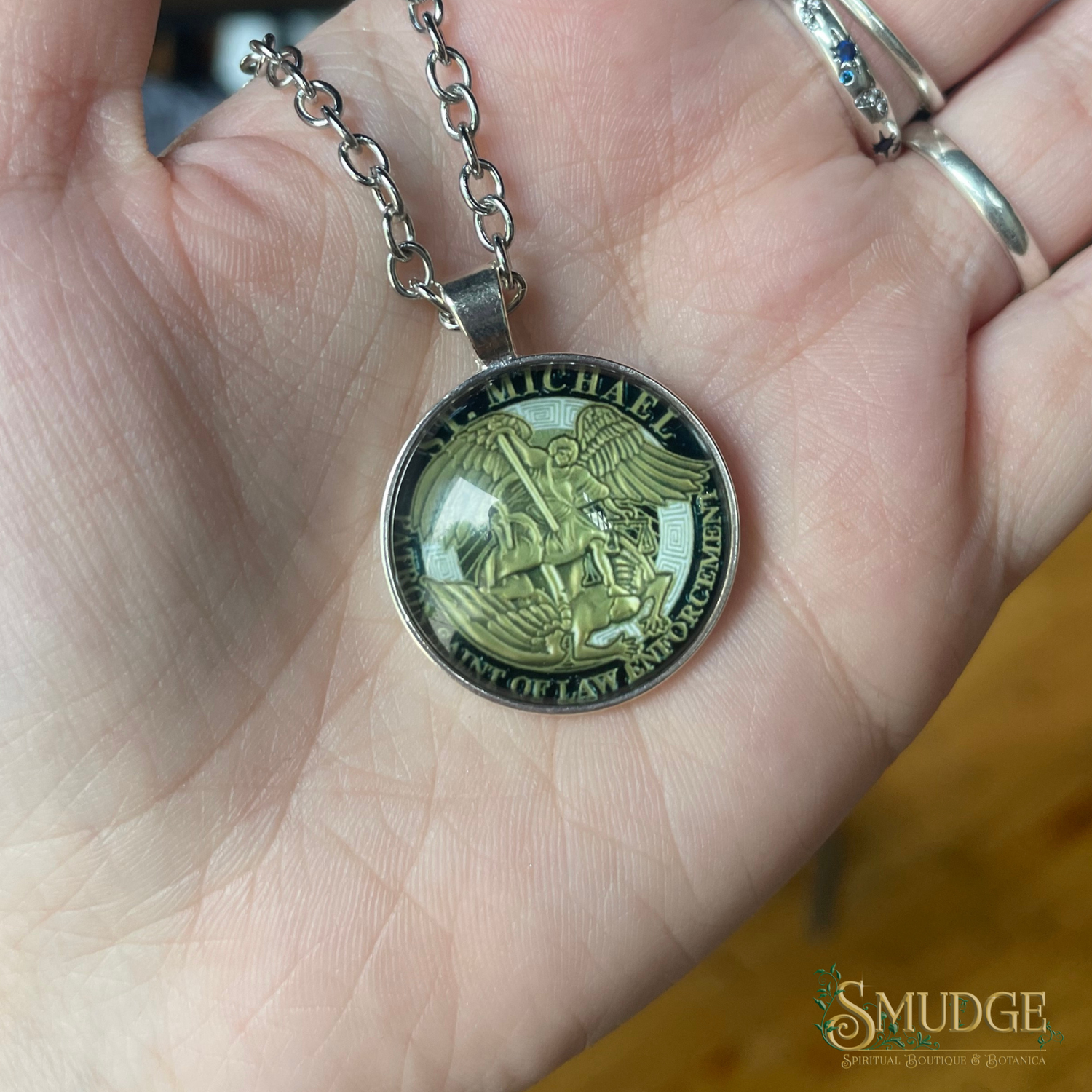 Close-up of a hand holding a necklace with a pendant featuring an angelic design.