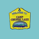Pin with 'Welcome to Camp Crystal Lake' text on a textured gray background