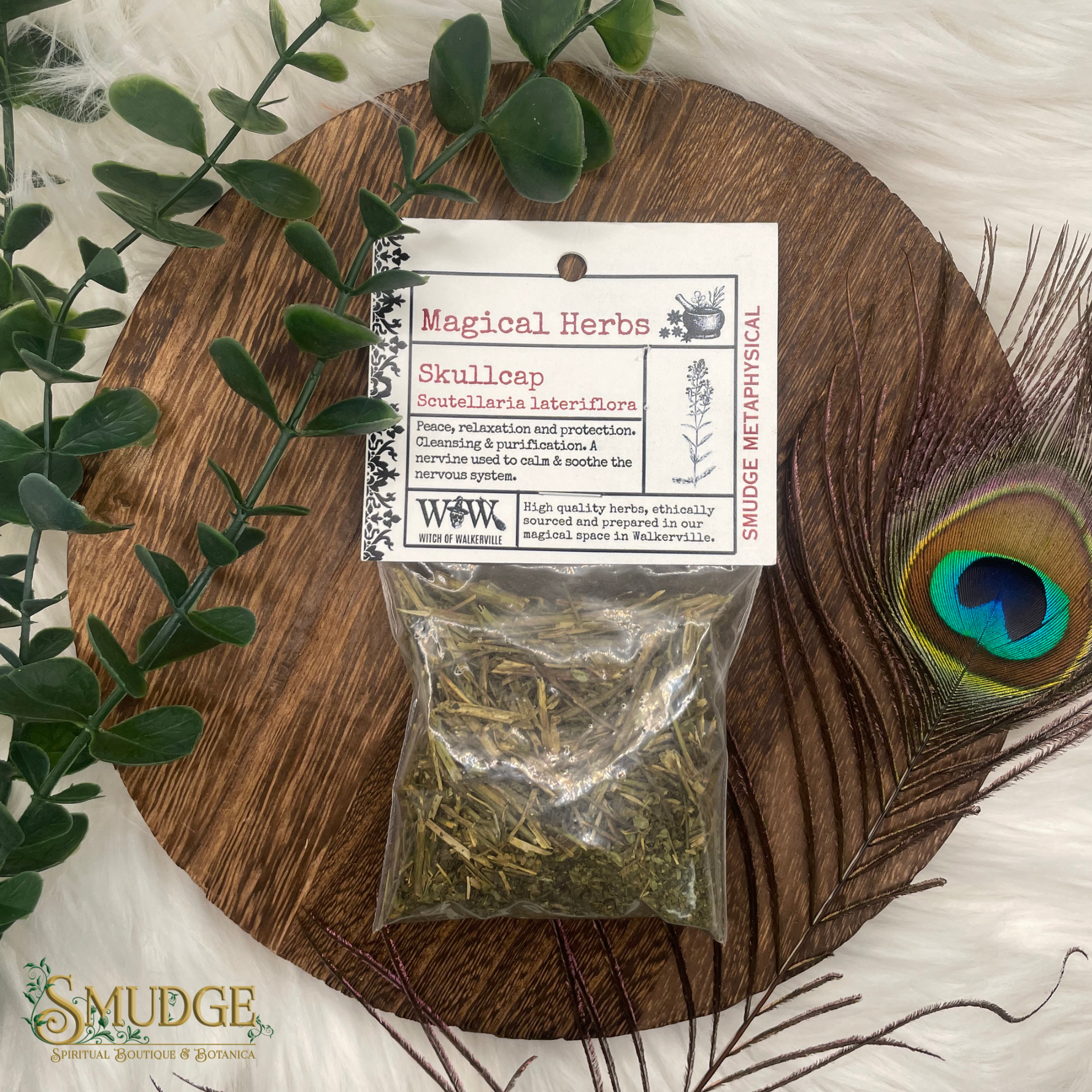 Bag of skullcap herbs on a wooden board with a peacock feather and eucalyptus leaves.