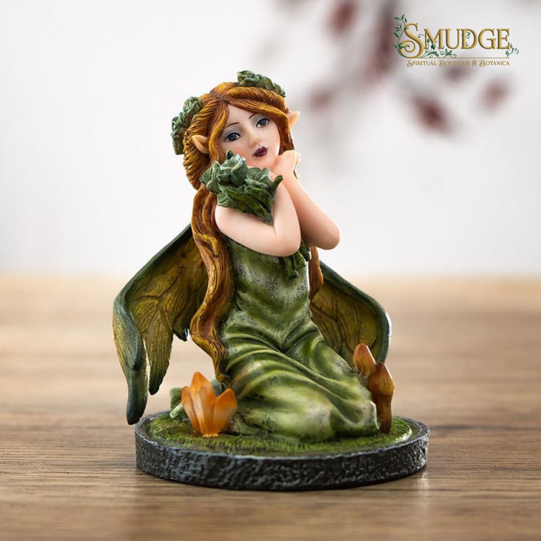 Elf figurine with green dress and wings holding a leaf, branded 'Smudge'.