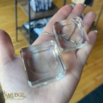 Clear crystal cubes held in a hand with a blurred indoor background