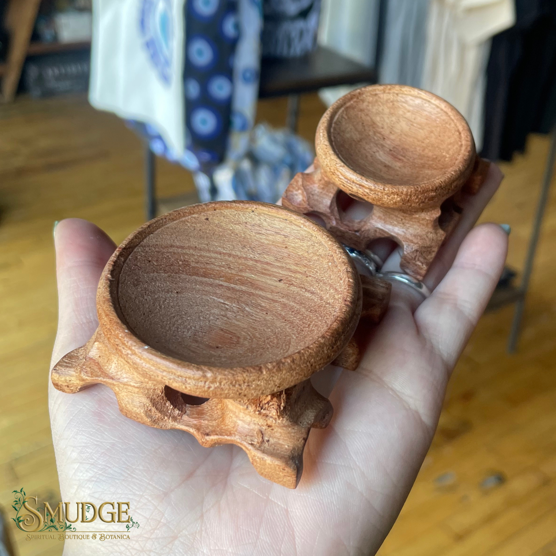Wooden crystal ball holder held in a hand with a blurred indoor background