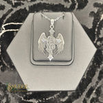 Silver pendant with wings on a hexagonal gray stand, brand 'Smudge' visible