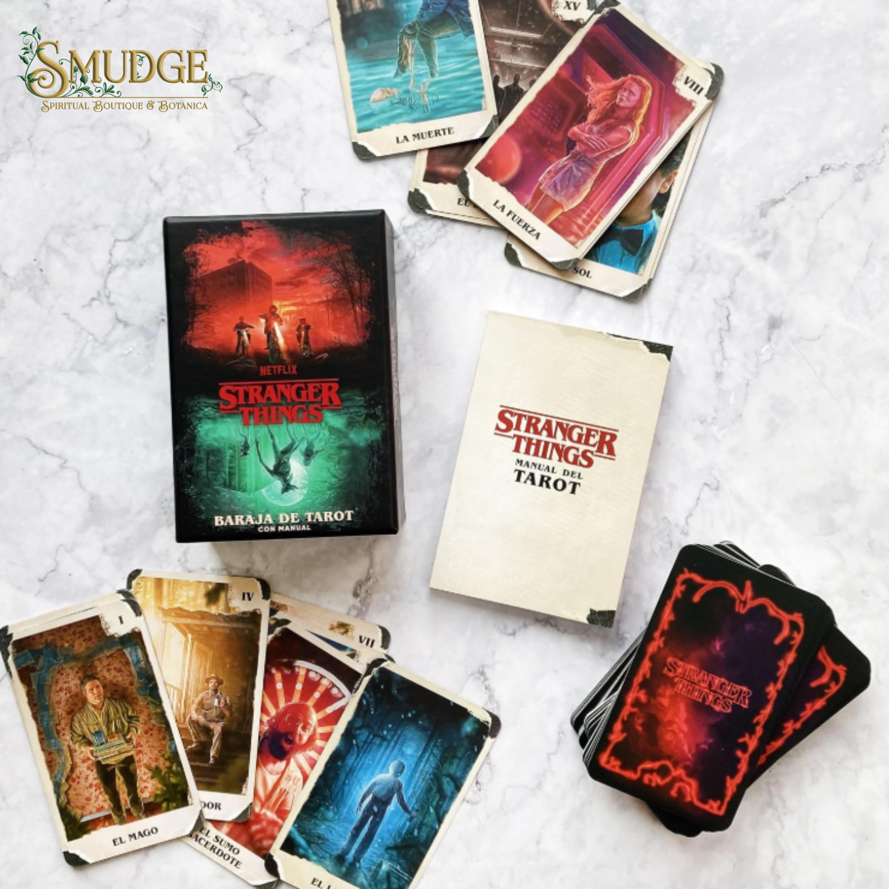 Stranger Things Bakaja de Tarot deck and box set displayed on a white marble background, showing the main box, a booklet, a stack of cards, and several individual tarot cards.
