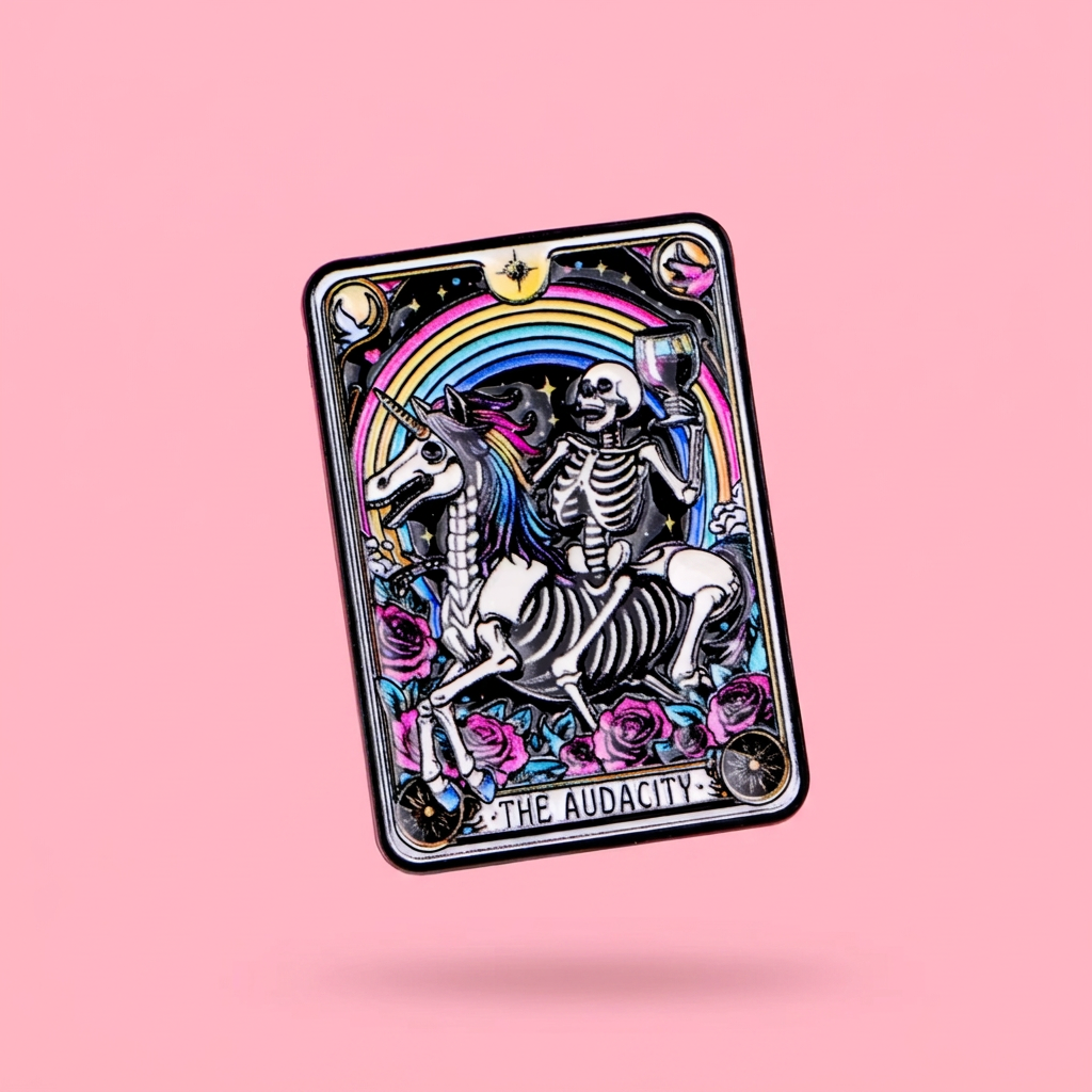 A small rectangular enamel pin featuring a tarot-style skeleton riding a unicorn with a rainbow, roses, and stars,  against a pink background.