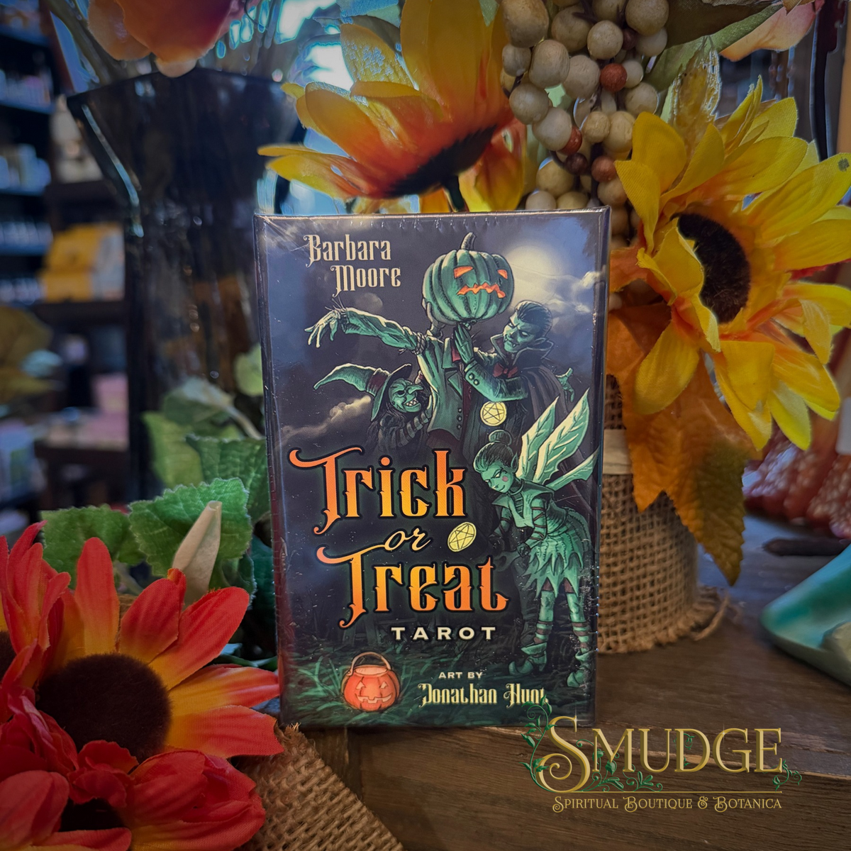 Trick or treat Tarot deck on a wooden table with sunflowers around it.