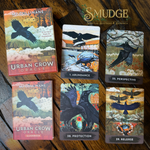 Urban Crow Oracle card deck box and guidebook displayed with five illustrated oracle cards on a dark wooden surface. The box and cards feature raven and crow artwork with titles including 1.