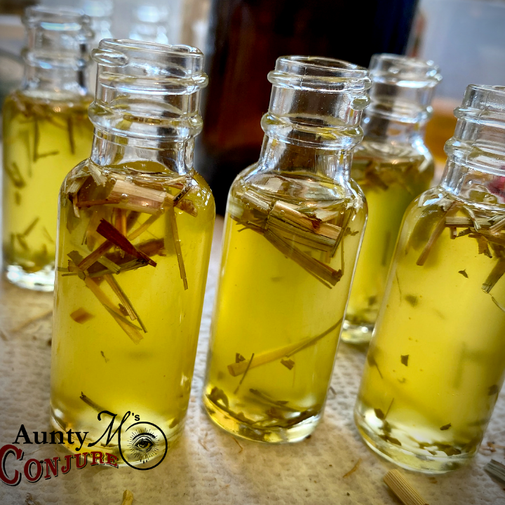 Small glass bottles filled with a yellow liquid and herbs, branded 'Aunty M's Conjure'.