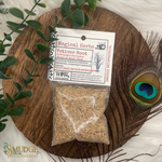Packaged vetiver root with a label on a wooden board with a peacock feather and greenery.