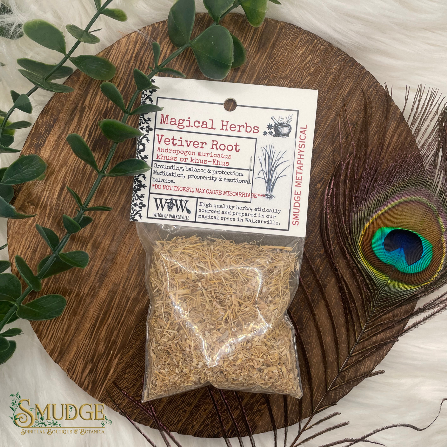 Packaged vetiver root with a label on a wooden board with a peacock feather and greenery.