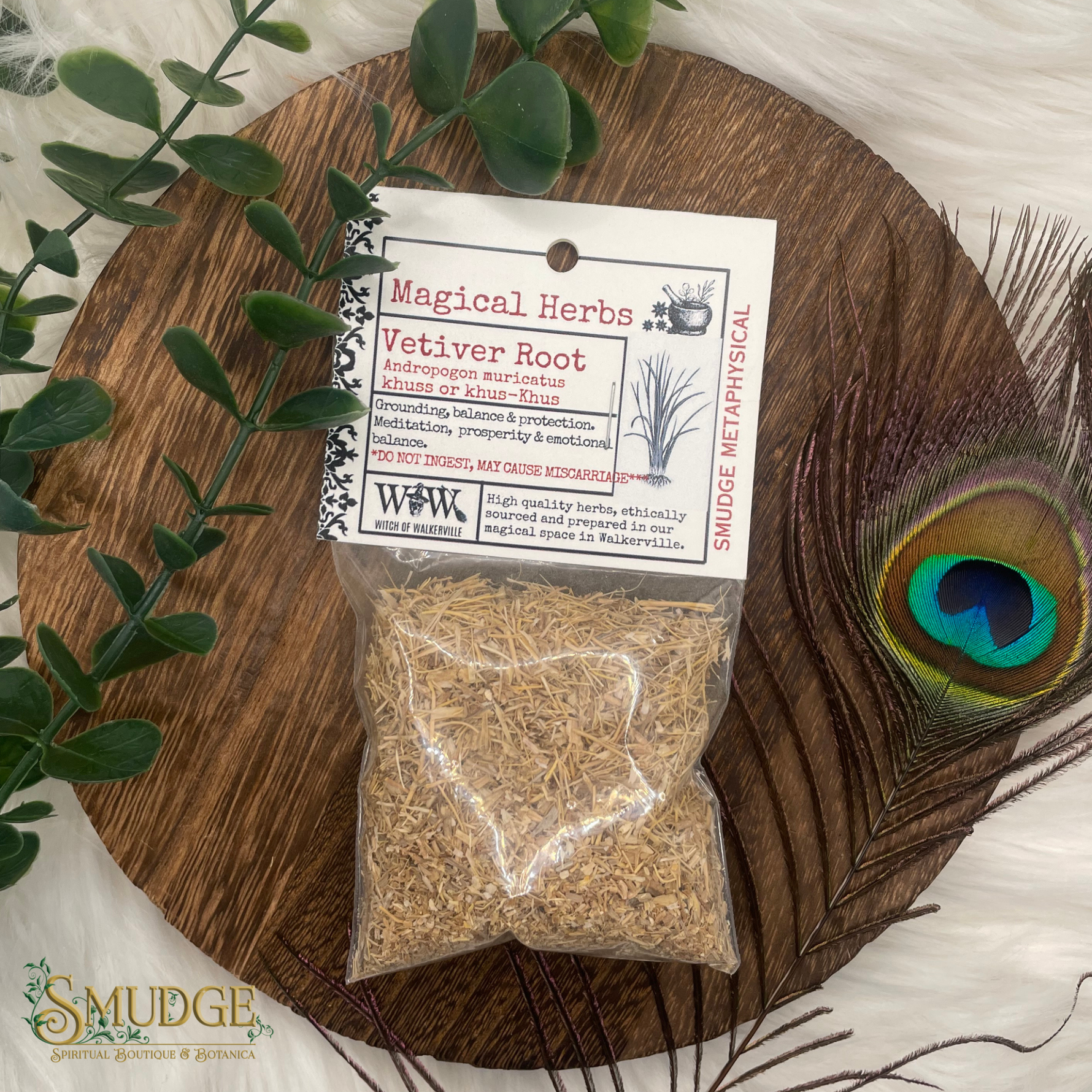 Packaged vetiver root with a label on a wooden board with a peacock feather and greenery.
