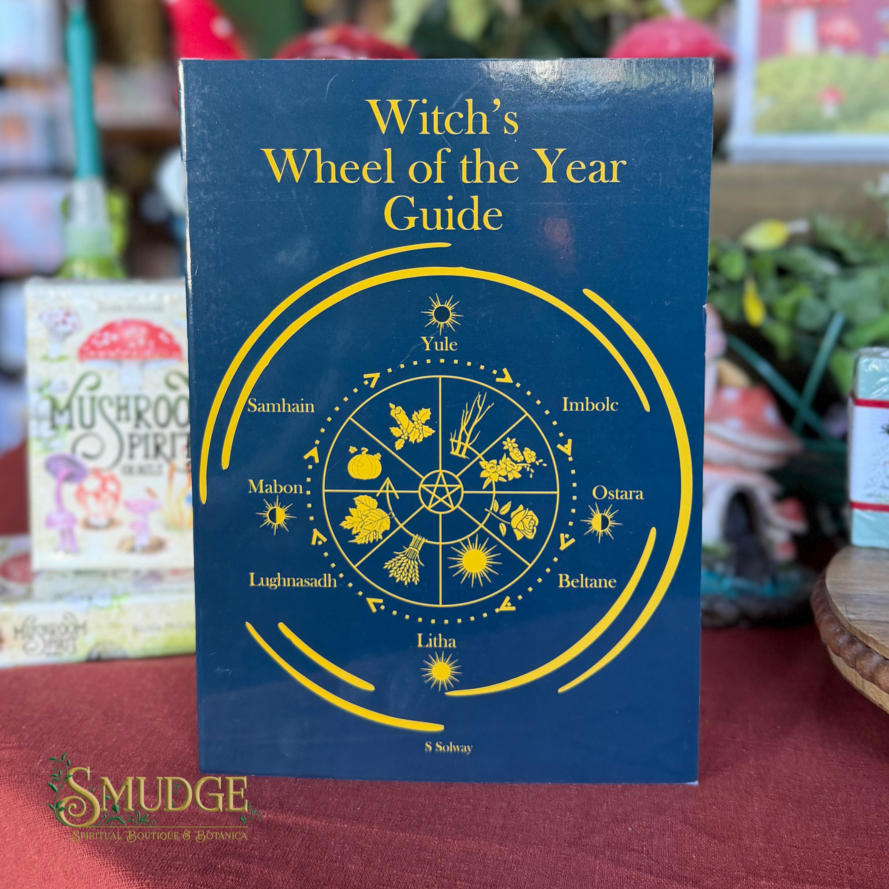 A book titled 'Witch's Wheel of the Year Guide' by S. Sobry, featuring a dark blue cover with a yellow astrological wheel diagram.