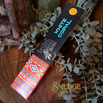 A box of Ethical Wood White Copal incense sticks by Smudge Spiritual Candles & Botanica, styled on a wooden surface with green eucalyptus leaves and crystals.