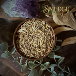 Wooden bowl with dried herbs on a wooden surface with 'Smudge' branding.