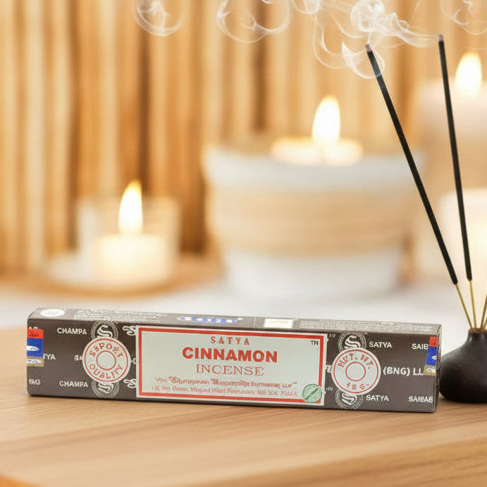 Box of Satya Cinnamon incense on a wooden stand with candles in the background